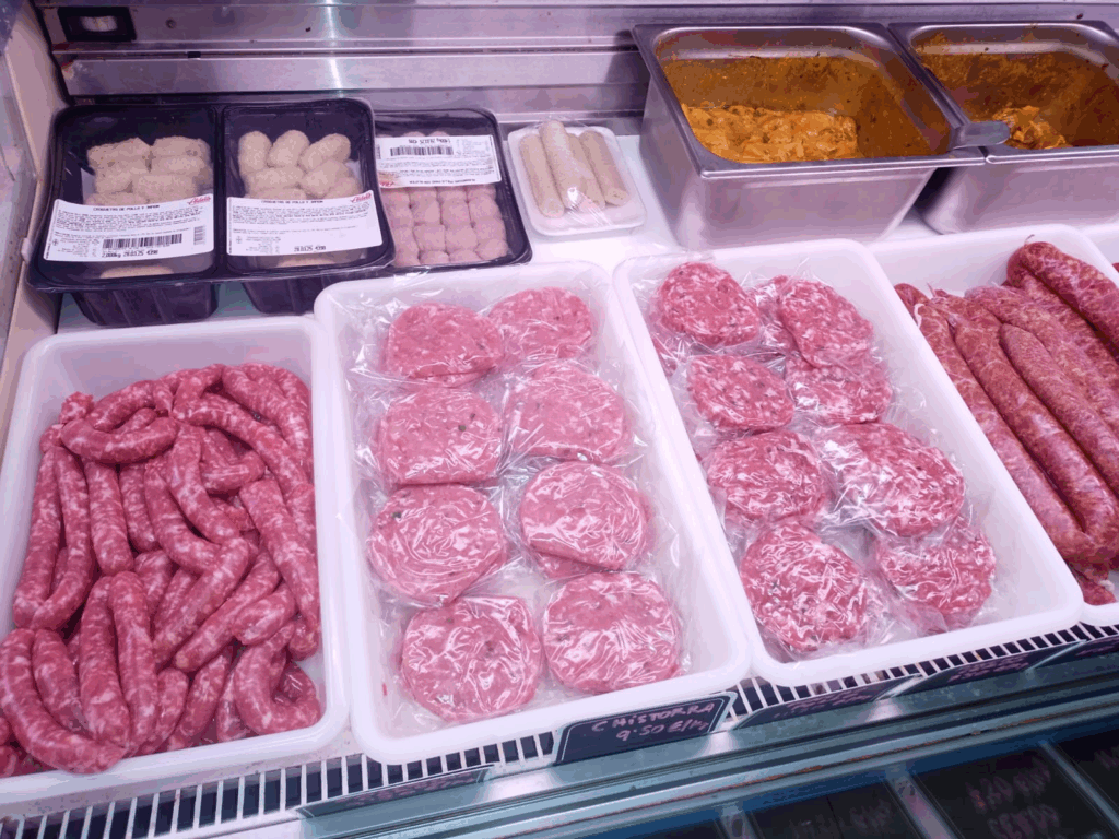 Mostrador refrigerado de carnicería con carne picada, hamburguesas, salchichas y pollo empaquetado fresco