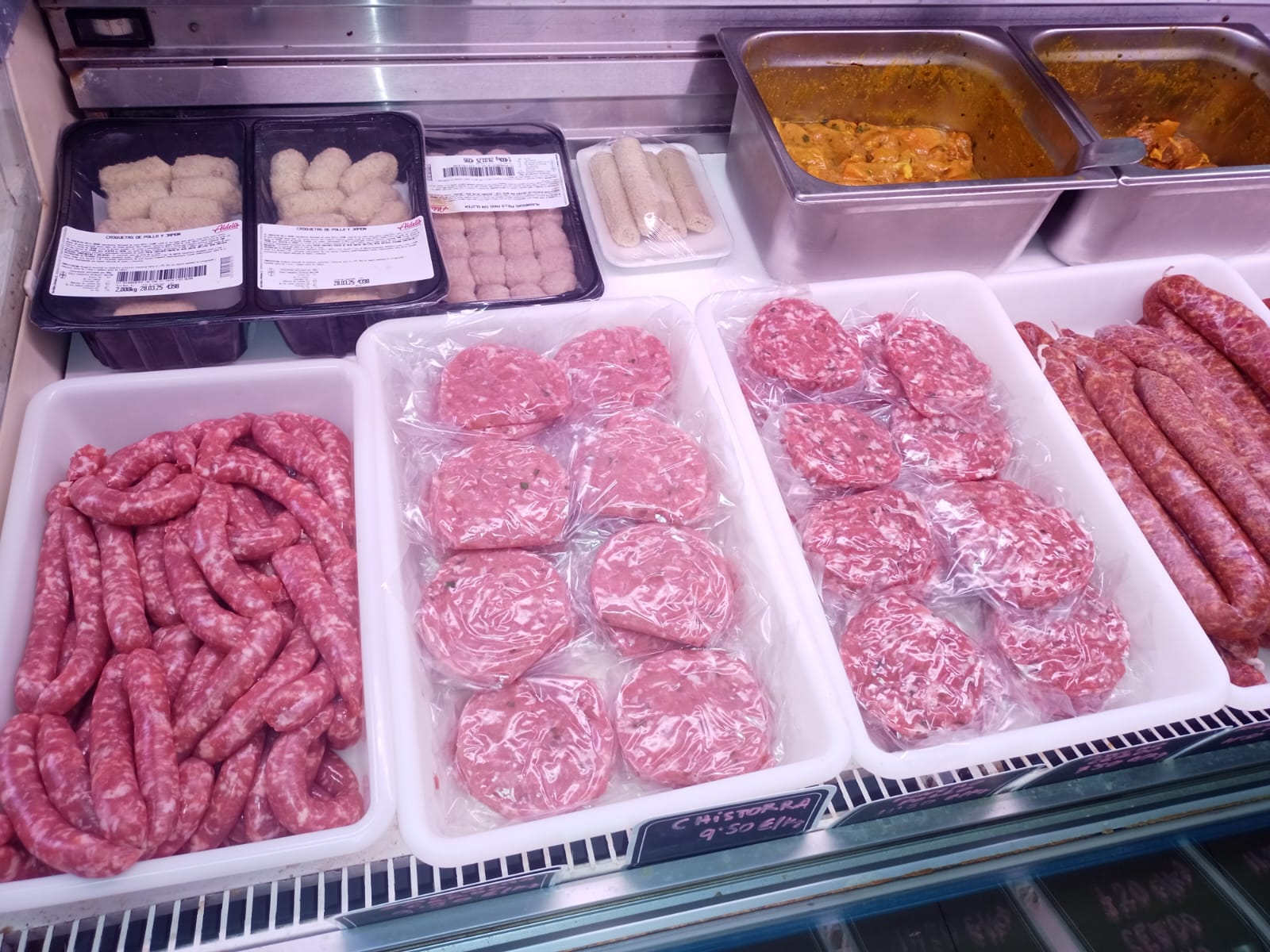 Mostrador refrigerado de carnicería con carne picada, hamburguesas, salchichas y pollo empaquetado fresco