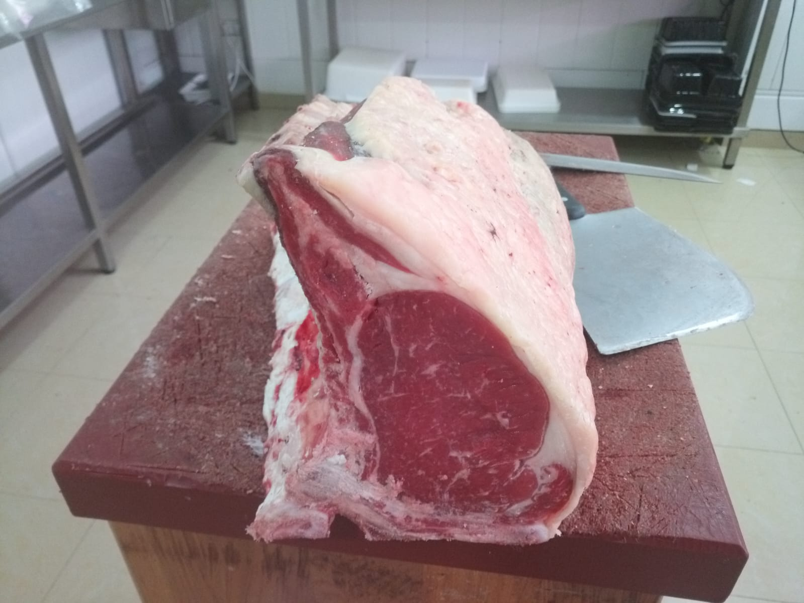 Pieza de carne de ternera cruda con grasa sobre tabla de corte en carnicería profesional