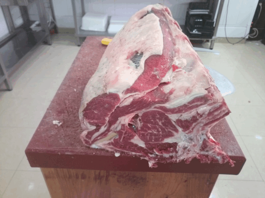 Costillar de cerdo ibérico fresco con hueso sobre tabla de madera en taller de despiece