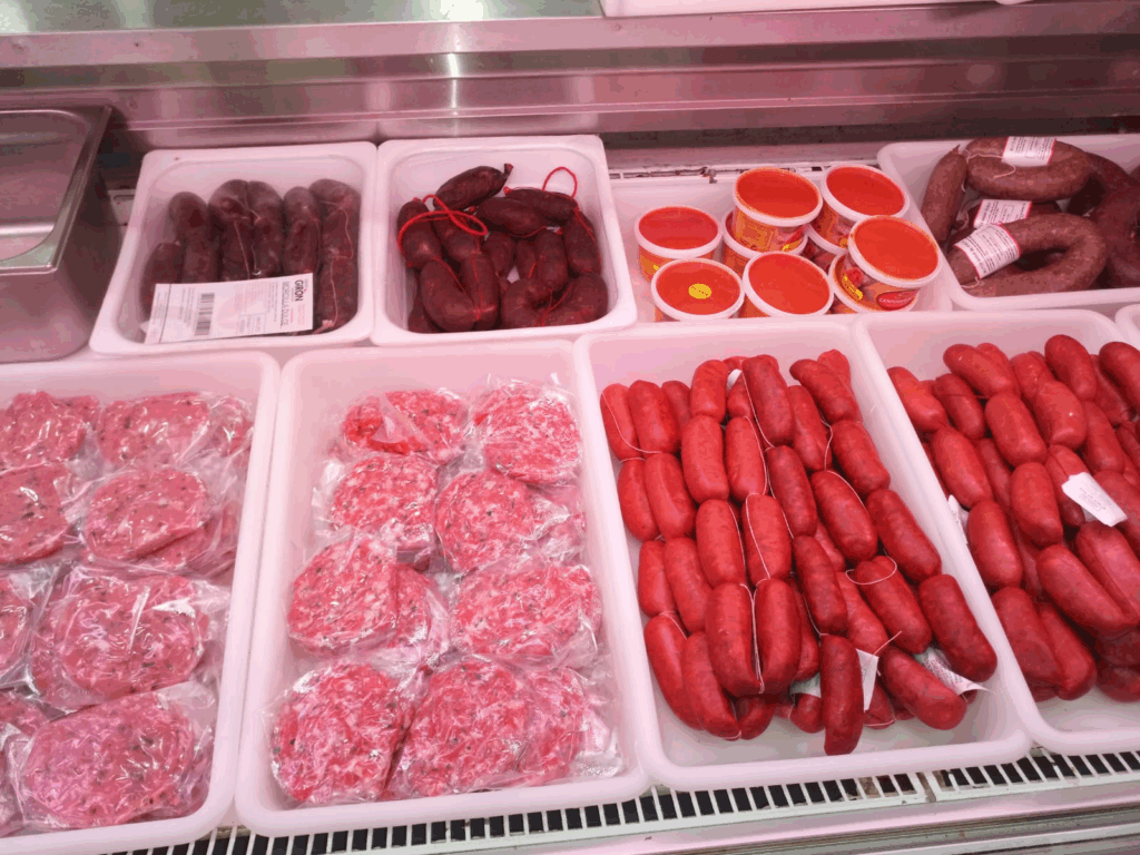 Mostrador refrigerado con selección de carnes frescas: hamburguesas, salchichas, morcilla y carne picada envasada