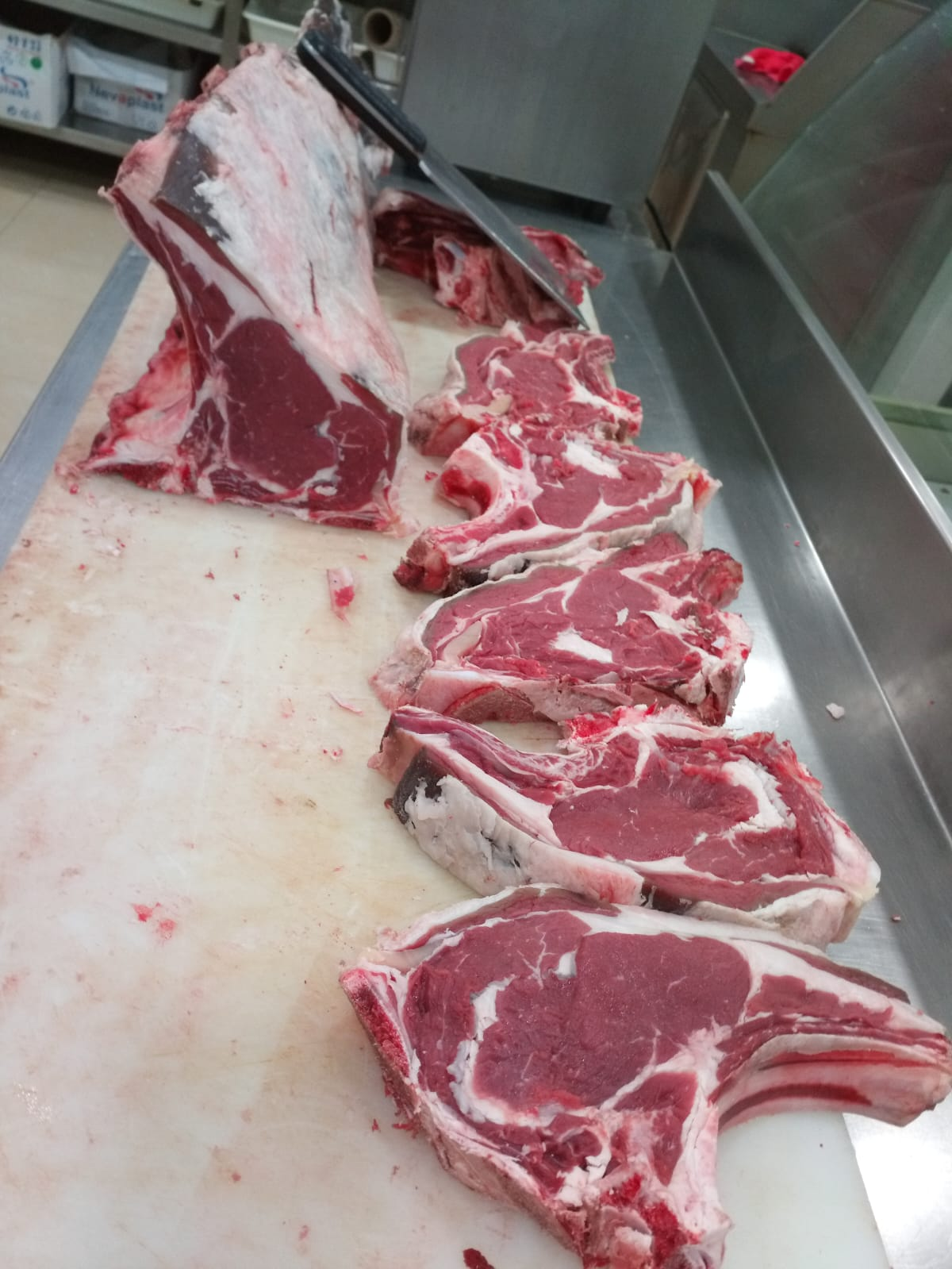Costillas de cerdo frescas con carne y grasa en proceso de despiece en carnicería